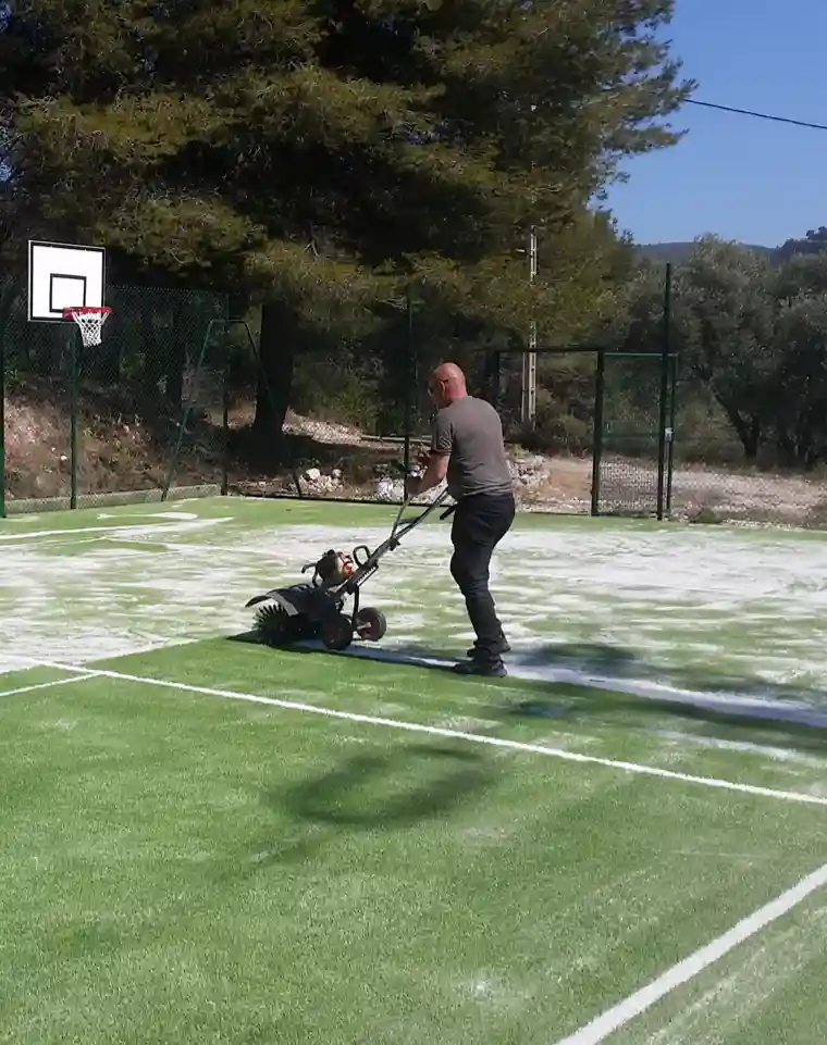 Entretien d'un terrain de sport en gazon synthétique avec machine de brossage
